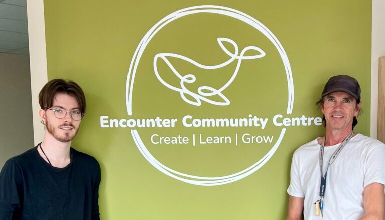 Two Jobseekers standing either side of the Encounter Community Centre sign.