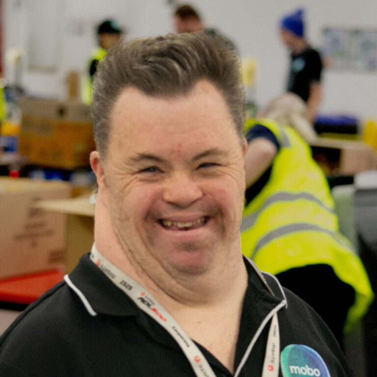Person with disability, wearing mobo shirt, smiling at camera