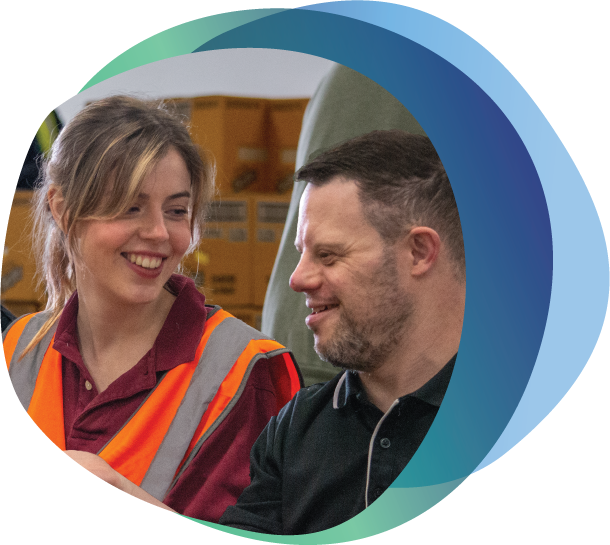 Person with a disability and female supervisor working together smiling at each other.