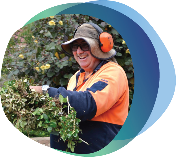 Man in Hi Vis Shirt carrying garden waste smiling