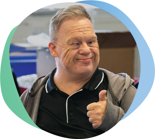 Person with disability smiling, giving 'thumbs up' to camera.