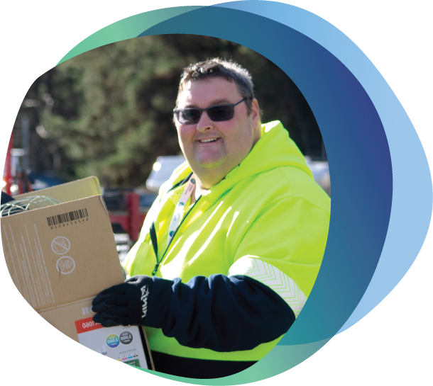 Person with a disability wearing Hi Vis Jumper receiving box of donated goods.